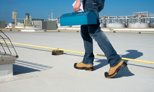 A contractor with a toolbox walking on Commercial Roofing in Scottsdale AZ