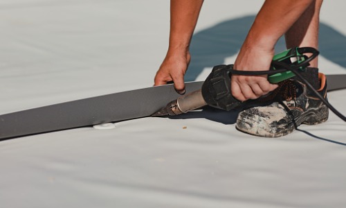 A contractor fixing a seam on a flat roof during Commercial Roof Repair in Phoenix AZ